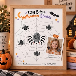 May include: A framed Halloween-themed art print featuring a spider web design with black fingerprint spiders, a crescent moon, a bat, and stars. The text reads Itsy Bitsy Halloween Spider, Name: Emma, and Date: 10/31/2024, with a photo of a child attached.