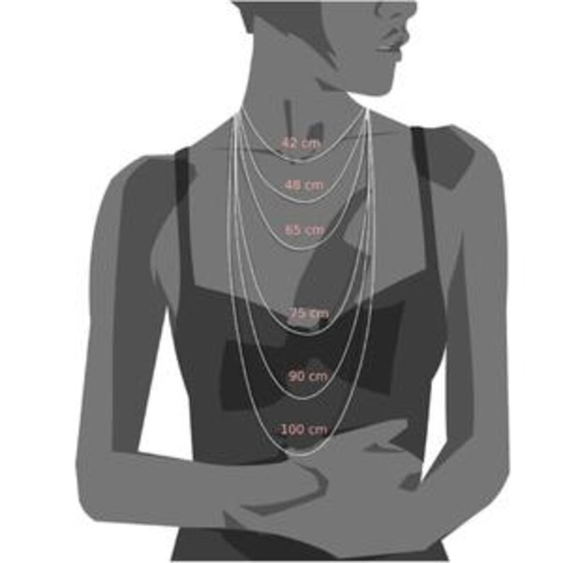 May include: A set of six silver-toned chains displayed on a silhouette, with lengths labeled as 42 cm, 48 cm, 65 cm, 75 cm, 90 cm, and 100 cm. The chains vary in length, creating a layered effect against the dark gray torso outline.