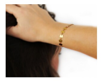 May include: A gold bracelet with a chain of small, round discs.