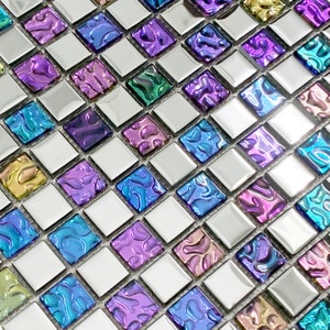 Puede incluir: Primer plano de azulejos de mosaico iridiscentes con fondo plateado. Los azulejos están dispuestos en forma de rombo y presentan una variedad de colores, incluyendo morado, azul y verde.