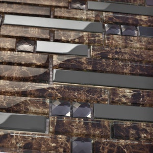 Puede incluir: Azulejos de mosaico de vidrio marrón y negro con acabado espejado y detalles de vidrio transparente. Los azulejos tienen un aspecto texturizado y marmoleado.