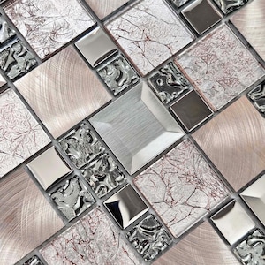 May include: Close-up of a mosaic tile pattern featuring a mix of textures and colors. The design includes square and rectangular tiles in brushed metal, silver, and textured glass with a reddish-brown veining pattern. The overall effect is a modern, geometric design.