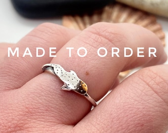 May include: A silver ring featuring a stylized seahorse design with a textured body and a smooth, curved tail. The ring is worn on a finger, with the text "MADE TO ORDER" in white across the top.