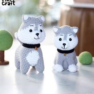 May include: Two crocheted husky dog plushies, one standing and one sitting. Both are gray and white with black collars and gold bells.