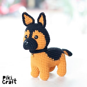 K&ouml;nnte beinhalten: Ein geh&auml;keltes Stofftier in Form eines Deutschen Sch&auml;ferhundes. Der Hund ist braun und schwarz mit einer schwarzen Nase und schwarzen Augen. Der Hund tr&auml;gt eine goldene Glocke um den Hals.