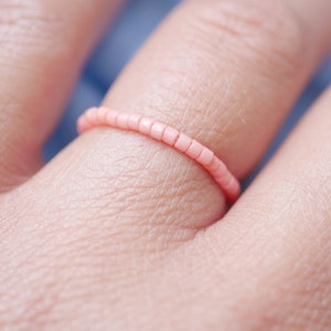 Peut inclure: Gros plan d'une bague en perles roses portée à un doigt.