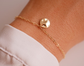 May include: A gold chain bracelet with a hammered gold disc charm.
