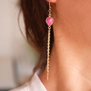 Peut inclure: Boucles d'oreilles pendantes dorées avec un pendentif en pierre précieuse rose.