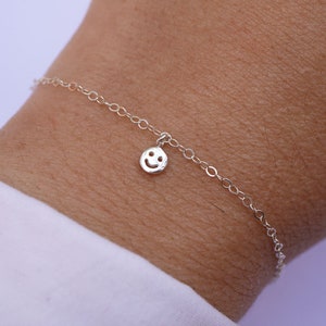 Peut inclure: Un bracelet en chaîne argent avec un petit charme smiley en argent.