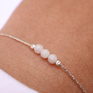 Könnte beinhalten: Ein zartes Armband aus Silberkette mit drei weißen Perlen.