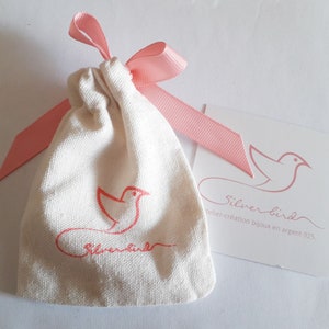 May include: A white drawstring bag with a pink ribbon and a pink bird logo. The bag is labeled "Silver Bird" and "atelier-creation bijoux en argent 925".