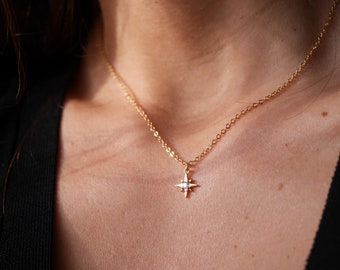 Puede incluir: Un collar de cadena dorada con un pequeño colgante de estrella con un cristal transparente en el centro.