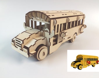 Puede incluir: Un modelo de madera de un autobús escolar amarillo con las palabras "SCHOOL BUS" en el lateral. El modelo tiene una señal de stop en el lateral y está detallado con ventanas, puertas y ruedas. Un autobús escolar amarillo más pequeño se muestra en la esquina inferior derecha de la imagen.