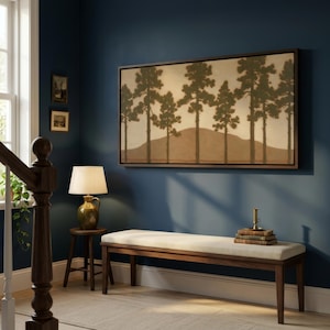 May include: A rectangular wall art piece featuring a landscape of tall pine trees in dark green against a muted beige background with a brown hill, framed in dark wood. The artwork is displayed above a long wooden bench with a light beige cushion.