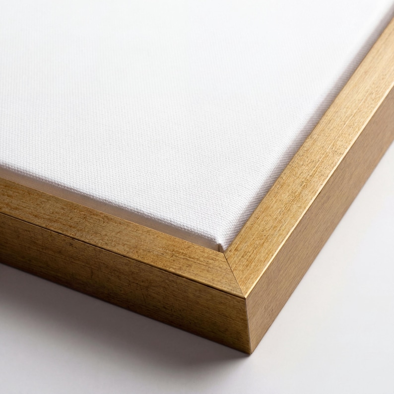 May include: Close-up of a canvas stretched over a wooden frame. The canvas is white, and the frame is a warm gold colour. The corner of the frame is visible, showing the construction and texture of the wood.