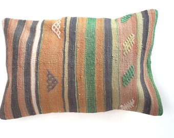 May include: A rectangular pillow with a striped pattern in shades of orange, green, black, and white. The pillow has a woven texture and features embroidered geometric designs.