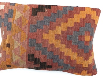 May include: A rectangular pillow with a geometric pattern in shades of orange, red, brown, and gray. The pillow is made of woven fabric and has a slightly textured surface.