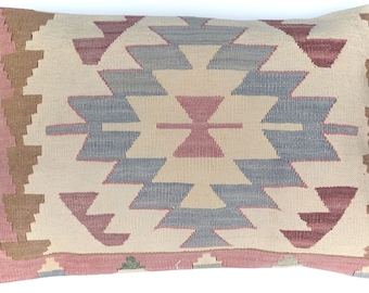 May include: A rectangular throw pillow with a geometric pattern in shades of brown, pink, and blue. The pillow has a woven texture and a fringe border.
