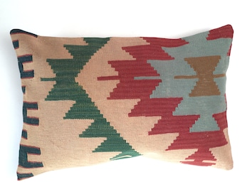 May include: A rectangular throw pillow with a geometric pattern in shades of red, green, blue, and brown. The pillow is made of woven fabric and has a soft, textured surface.