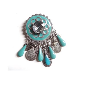 Puede incluir: Un colgante turquesa y plateado con un gran cristal en el centro y colgantes de turquesa y plata.