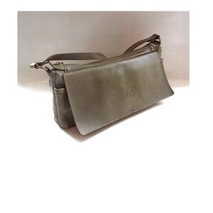 May include: A gray leather crossbody bag with a flap closure and a zippered pocket on the front.