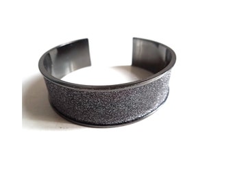 May include: A wide silver bangle bracelet with a sparkly silver band.