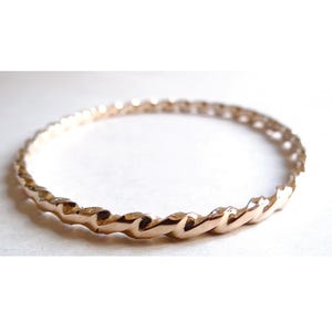 Peut inclure: Un bracelet jonc doré avec un motif torsadé en forme de corde. Le bracelet circulaire semble être en métal. Le motif torsadé donne au bracelet un aspect texturé. Ce bijou convient au quotidien.