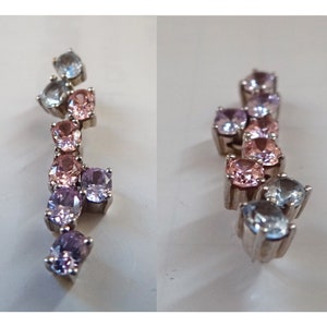 May include: A silver pendant with a graduated row of pink, purple, and blue gemstones.