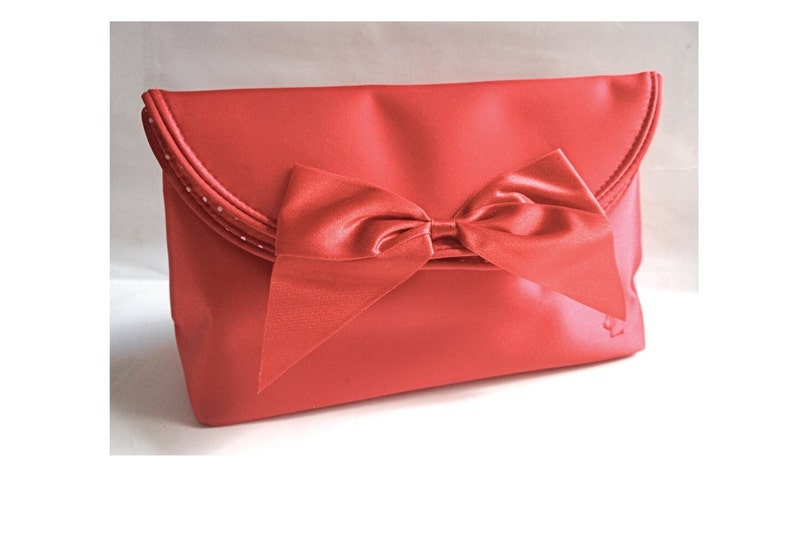 May include: A red satin clutch with a large satin bow.