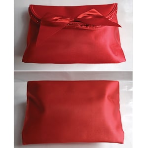 May include: A red satin clutch bag with a large bow and a small logo on the front.