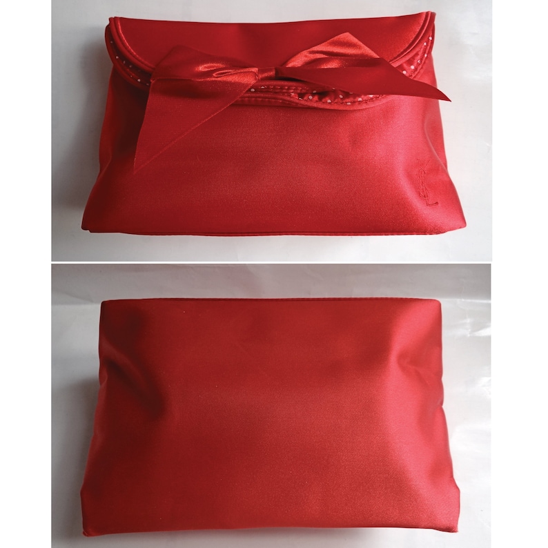 May include: A red satin clutch bag with a large bow and a small logo on the front.