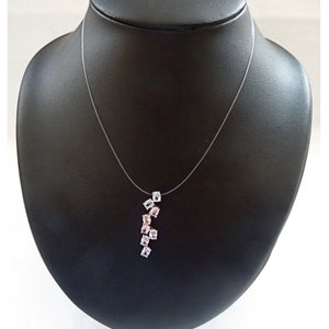 May include: A delicate necklace with a clear, thin chain and a pendant featuring a cluster of pink and blue gemstones. The pendant is shaped like a teardrop and the gemstones are arranged in a cascading pattern.
