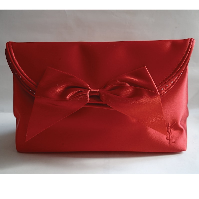 May include: A red satin clutch bag with a large bow and a YSL logo.