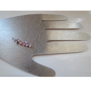 May include: A silver earring with a cluster of pink and clear rhinestones.