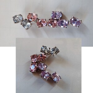 May include: Two silver charm bracelets with pink, purple, and blue oval-shaped gemstones. The charms are connected by a silver chain.
