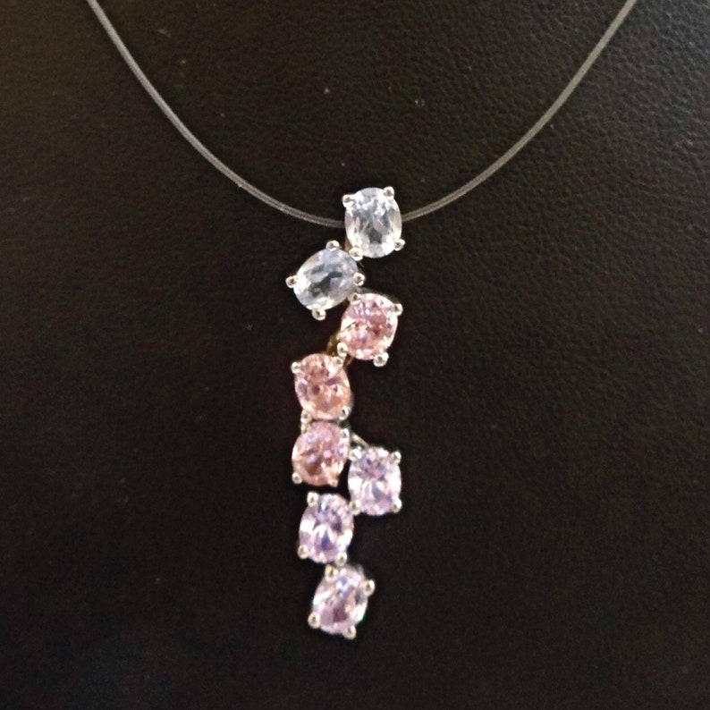 May include: A silver necklace with a clear and pink crystal pendant. The pendant features a cluster of oval and round crystals arranged in a cascading design.