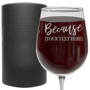 May include: A clear glass wine glass with the text "Because [YOUR TEXT HERE]" etched on the side. The glass is filled with red wine and is sitting in a black box.