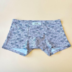Puede incluir: Bóxer blanco con estampado floral azul y blanco. La cintura tiene el texto "Good Vibrations" impreso.