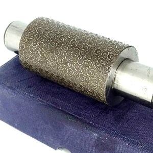 May include: A silver metal roller with a textured surface, in a blue velvet box.