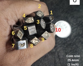 May include: A set of ten metal stamps with different designs, including a flower, a bird, a wave, and a star. The stamps are arranged in a circle and are held in a hand. The coin in the background is 25.4mm (1 inch) in diameter.