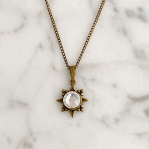 May include: A gold chain necklace with a star-shaped pendant featuring a clear crystal in the center.