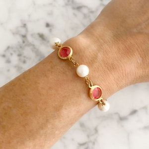 Könnte beinhalten: Ein goldenes Armband mit rosa und weißen Perlen. Das Armband hat eine zarte Kette und verfügt über abwechselnde rosa und weiße runde Perlen.