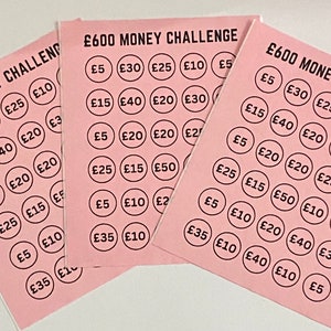 May include: Four pink cards with the text "&pound;600 MONEY CHALLENGE" printed on them. Each card has a grid of 30 circles with different amounts of money printed inside each circle, such as &pound;5, &pound;10, &pound;15, &pound;20, &pound;25, &pound;30, &pound;35, &pound;40, and &pound;50.