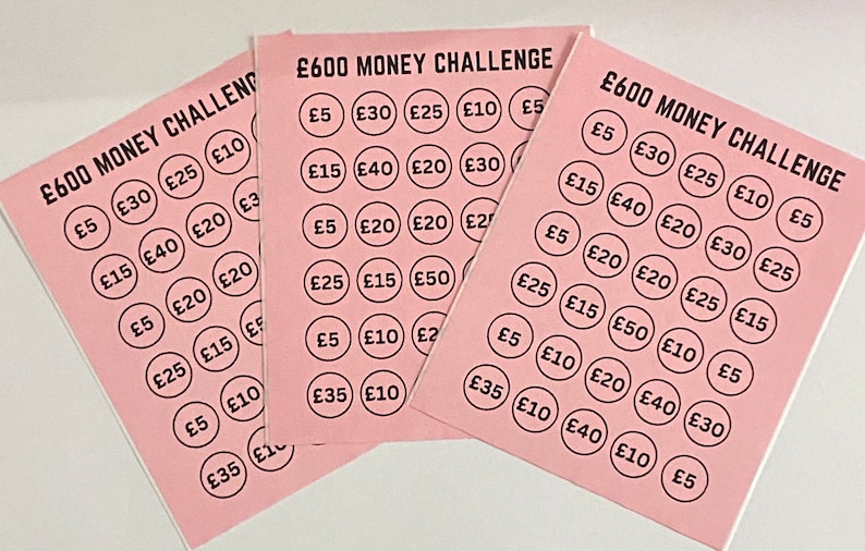 May include: Four pink cards with the text "&pound;600 MONEY CHALLENGE" printed on them. Each card has a grid of 30 circles with different amounts of money printed inside each circle, such as &pound;5, &pound;10, &pound;15, &pound;20, &pound;25, &pound;30, &pound;35, &pound;40, and &pound;50.