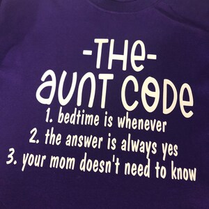 May include: Purple t-shirt with white text that reads "The Aunt Code" and lists three rules: "1. Bedtime is whenever", "2. The answer is always yes", and "3. Your mom doesn't need to know."