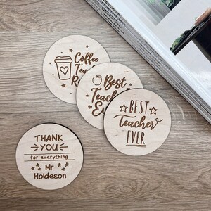 May include: Four round wooden coasters with engraved text. One coaster says "Coffee Tea Repeat" with a coffee cup icon. Another says "Best Teacher Ever" with a star. The third says "Best Teacher Ever" with a star. The fourth says "Thank You for everything Mr. Holdeson".