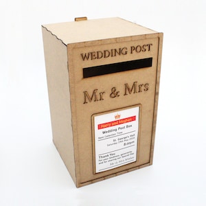 May include: A light brown wooden wedding post box with the words "WEDDING POST" and "Mr & Mrs" engraved on the front. A slot is cut into the front. A label reads "Harry and Meghan Wedding Post Box".