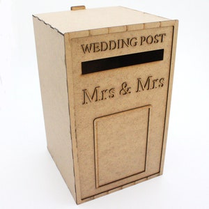 May include: A light brown wooden wedding post box with the words "WEDDING POST" and "Mrs & Mrs" engraved on the front. The box has a slot for cards and a small door. The box is rectangular and has a small wooden tab on top.