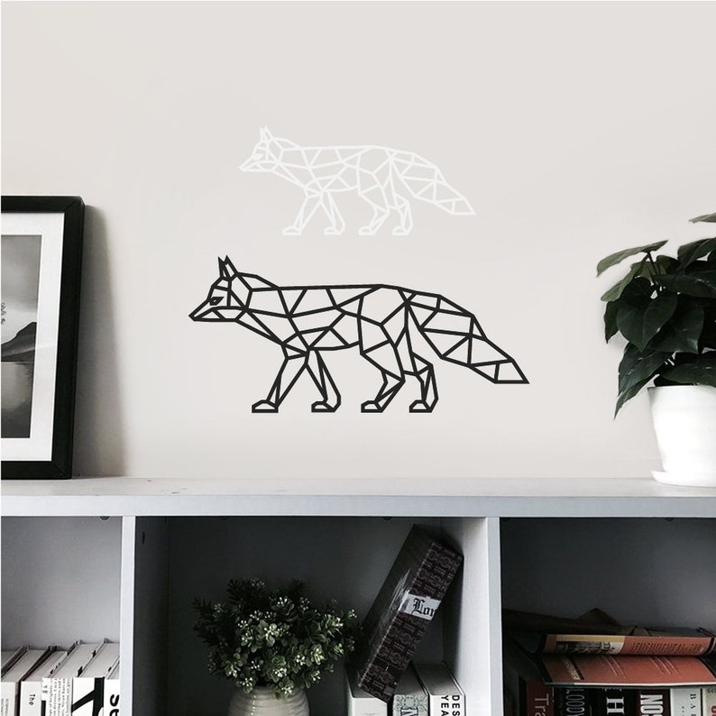 May include: A wall decal set featuring two geometric fox silhouettes. One fox is rendered in solid black lines, while the other is rendered in solid white lines. Both foxes are depicted in a walking profile pose with a triangular polygon design.