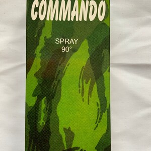 May include: A green and black camouflage patterned box with the text "COMMANDO" in white letters. The box also has the text "SPRAY 90°" and "EAU DE TOILETTE" in white letters.